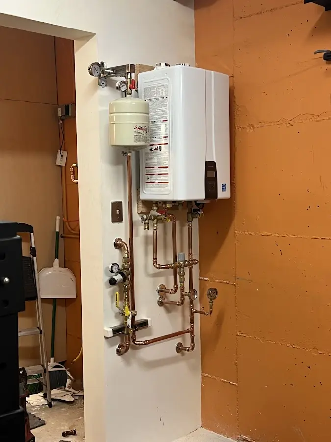 Plumbing technician inspecting water heater connections in Kennett